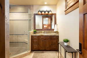 Bathroom featuring tile patterned flooring, vanity, and a shower with shower door