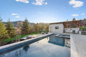 View of swimming pool with an in ground hot tub, a mountain view, a patio area, and exterior kitchen