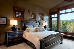 Bedroom featuring a mountain view, lofted ceiling, and light carpet