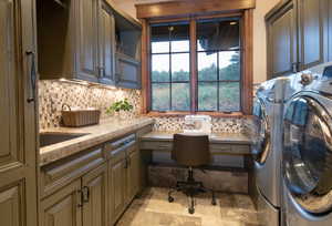 Clothes washing area featuring washing machine and clothes dryer and cabinets