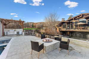 View of patio / terrace featuring a pergola, exterior kitchen, and a fire pit