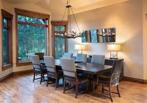 Dining room featuring light wood-type flooring, an inviting chandelier, and vaulted ceiling