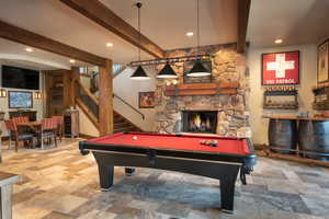 Recreation room with beamed ceiling, a stone fireplace, pool table, and bar