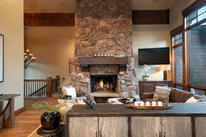 Living room featuring a fireplace, beam ceiling, hardwood / wood-style flooring, and an inviting chandelier