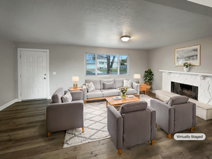 Living room featuring a textured ceiling, dark hardwood / wood-style flooring, and a stone fireplace