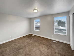 Spare room with dark carpet and a textured ceiling