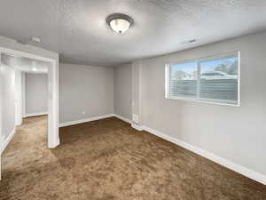 Basement with carpet flooring and a textured ceiling