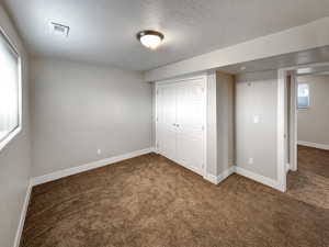 Unfurnished bedroom featuring a closet, carpet, and a textured ceiling