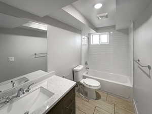 Full bathroom with toilet, vanity, and tiled shower / bath