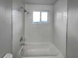 Bathroom featuring tiled shower / bath combo and toilet