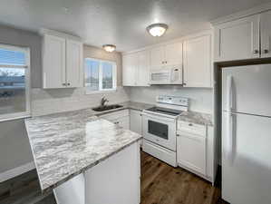 Kitchen with white cabinetry, sink, and white appliances