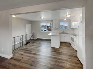 Kitchen with white cabinetry, sink, dark wood-type flooring, backsplash, and white appliances