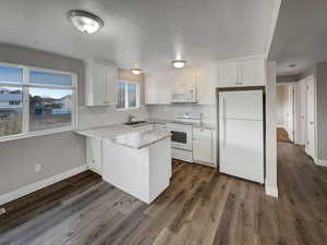 Kitchen with decorative backsplash, white cabinetry, white appliances, and sink