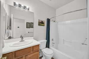 Full bathroom featuring vanity, shower / bath combination with curtain, and toilet