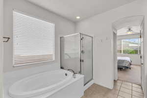 Bathroom with ceiling fan, tile patterned flooring, and shower with separate bathtub