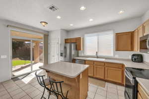 Kitchen featuring sink, a center island, stainless steel appliances, a breakfast bar area, and light tile patterned floors