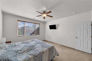 Bedroom with light carpet, a textured ceiling, and ceiling fan