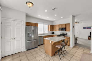 Kitchen with appliances with stainless steel finishes, a breakfast bar, ceiling fan, sink, and a kitchen island