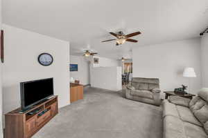 Carpeted living room with ceiling fan and a textured ceiling