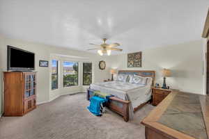 Carpeted bedroom featuring ceiling fan and a textured ceiling