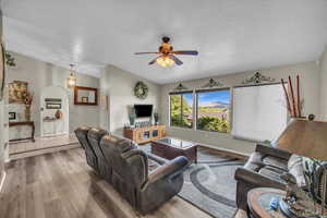 Living room with hardwood / wood-style floors, a textured ceiling, vaulted ceiling, and ceiling fan