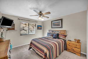 Carpeted bedroom featuring a textured ceiling and ceiling fan