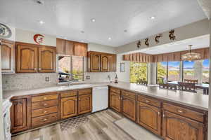 Kitchen with kitchen peninsula, white appliances, an inviting chandelier, and a healthy amount of sunlight