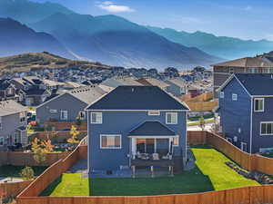 Rear view of property with a mountain view, outdoor lounge area, a patio, and a lawn