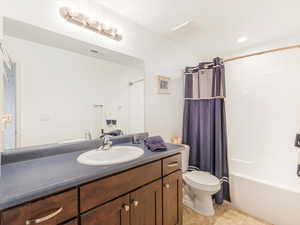 Full bathroom featuring tile patterned floors, vanity, shower / bath combination with curtain, and toilet