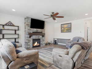 Living room featuring a fireplace, ceiling fan, and light hardwood / wood-style flooring