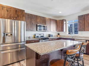 Kitchen with a kitchen breakfast bar, a center island, stainless steel appliances, and light hardwood / wood-style flooring