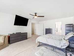 Bedroom with connected bathroom, ceiling fan, and light colored carpet