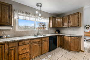 Kitchen featuring dishwasher, tasteful backsplash, hanging light fixtures, and sink