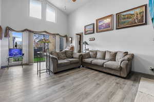 Living room featuring hardwood / wood-style flooring, ceiling fan, and high vaulted ceiling