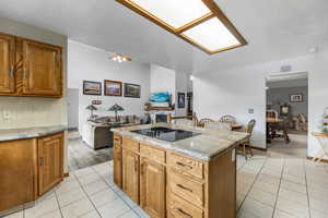 Kitchen with light stone countertops, ceiling fan, light tile patterned floors, black electric stovetop, and a kitchen island