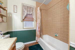 Full bathroom featuring vanity, hardwood / wood-style flooring, toilet, shower / bath combo with shower curtain, and a textured ceiling