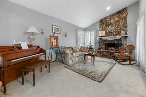 Carpeted living room featuring a fireplace and vaulted ceiling