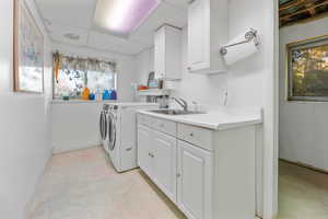 Laundry area featuring washing machine and dryer, sink, and cabinets