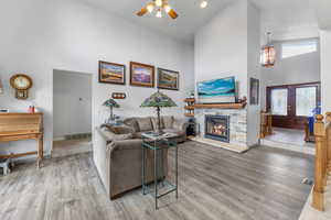 Living room with light wood-type flooring, a fireplace, high vaulted ceiling, and french doors