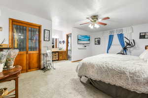 Bedroom with ensuite bath, ceiling fan, sink, light colored carpet, and a textured ceiling