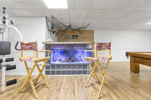 Playroom featuring a paneled ceiling, wooden walls, and hardwood / wood-style floors