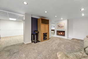 Carpeted living room featuring a tile fireplace and a drop ceiling