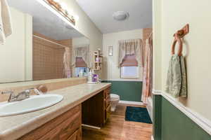 Bathroom featuring wood-type flooring, vanity, a textured ceiling, and toilet