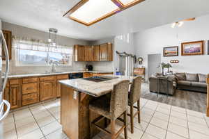 Kitchen featuring sink, a center island, a kitchen breakfast bar, light hardwood / wood-style floors, and decorative light fixtures