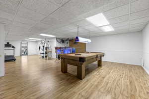 Playroom with a drop ceiling, billiards, and light wood-type flooring