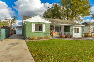 View of front facade featuring a porch, a garage, an outbuilding, and a front lawn