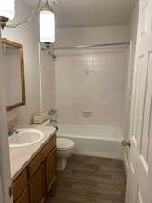 Full bathroom featuring hardwood / wood-style floors, vanity, tiled shower / bath combo, and toilet