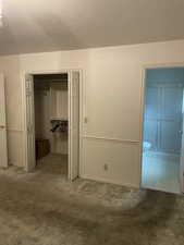 Unfurnished bedroom with ensuite bathroom, a textured ceiling, and a closet