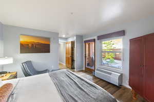 Bedroom with a wall mounted AC and dark hardwood / wood-style floors