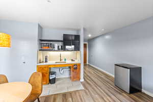 Kitchen featuring sink, backsplash, kitchen peninsula, appliances with stainless steel finishes, and light wood-type flooring